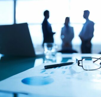 Business team meeting in a conference room with charts, a laptop and reading glasses on the table.